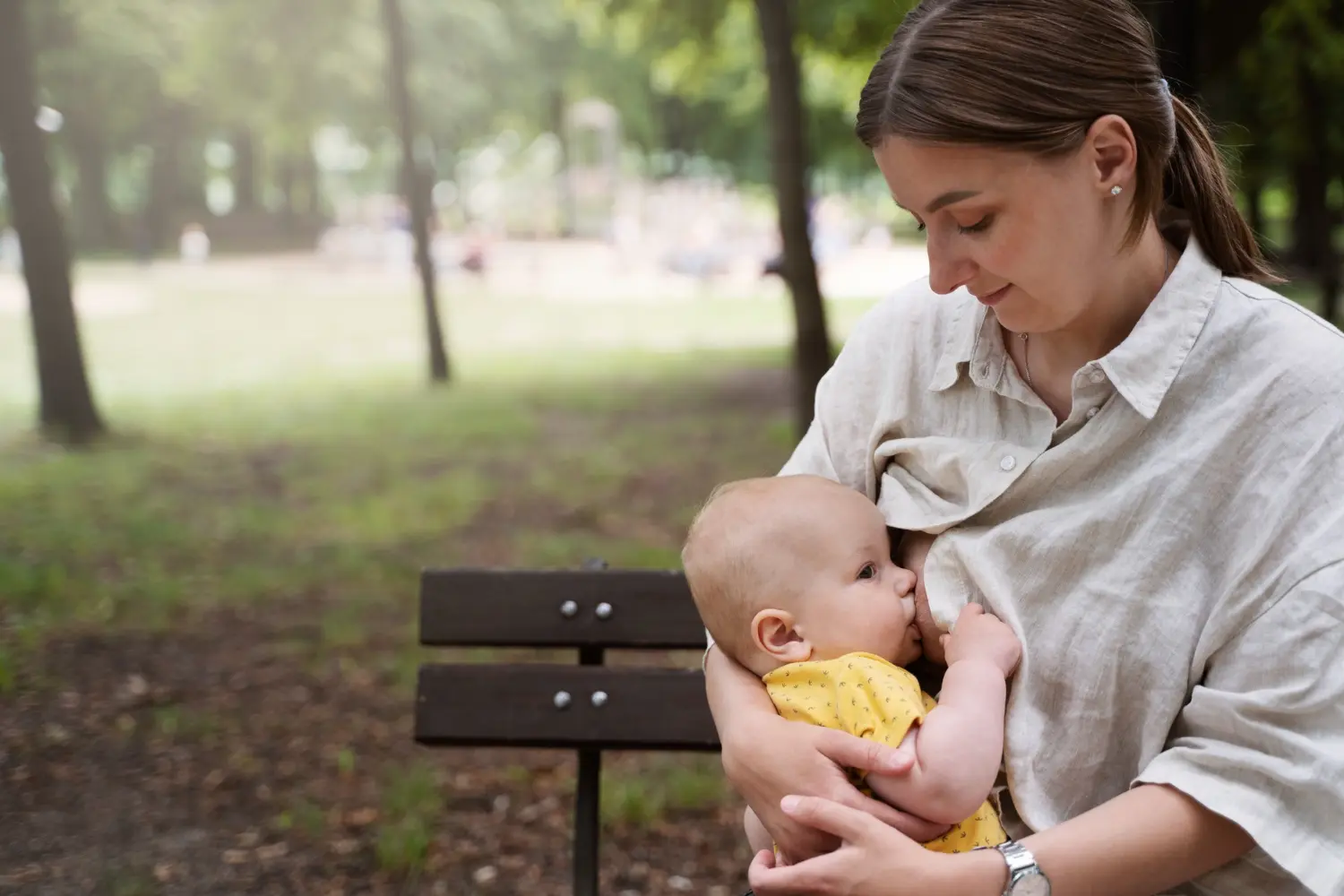 Madre amamantando a su bebé en un parque durante una etapa de lactancia y destete respetuoso